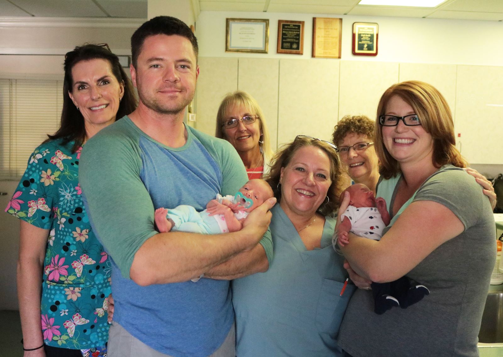 birth_center_twins A Father and Mother holding their newborn twins, joined by staff of hospital