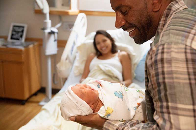 Mother watching Father hold newborn baby